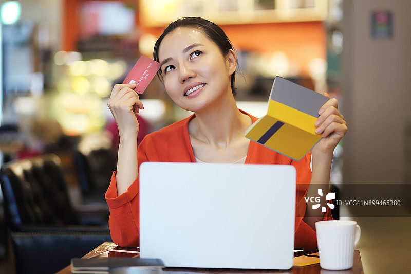 在咖啡馆拿着信用卡和银行存折的女人图片素材