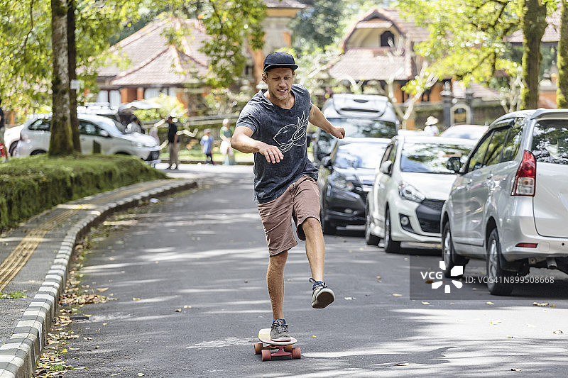 在印度尼西亚巴厘岛勿都古，站在街上手持滑板的男人正面图图片素材