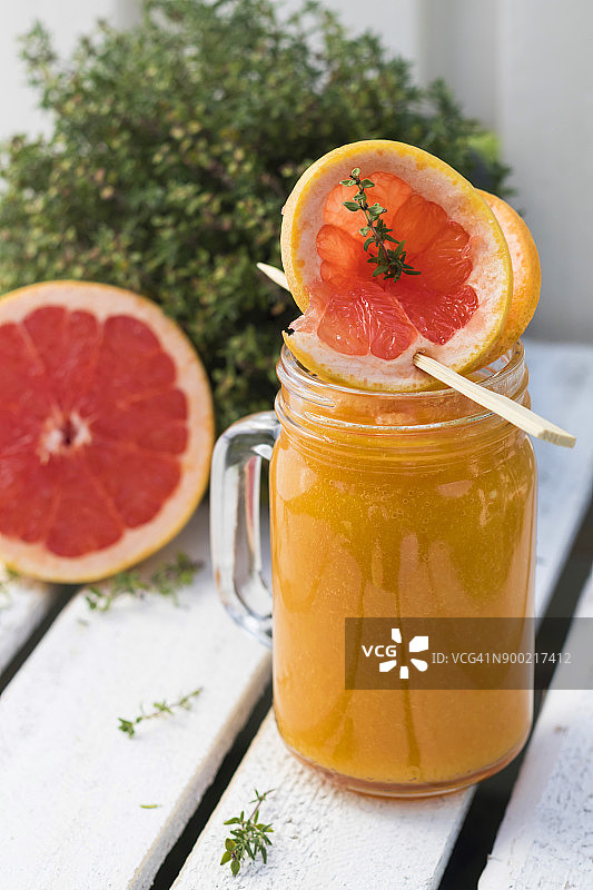 一杯含有葡萄柚、橙子、芒果和百里香的果蔬冰沙图片素材