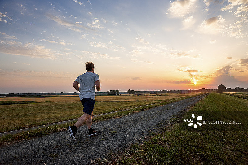 日落时分男子在乡村风景中奔跑图片素材