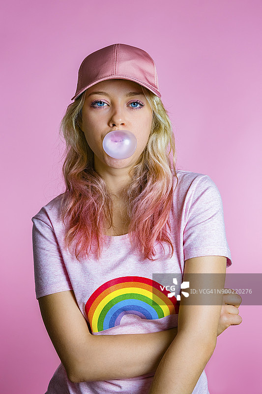 年轻女人嚼泡泡糖肖像，粉色背景图片素材