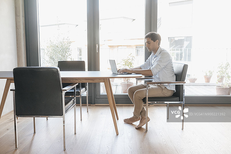 在桌旁使用笔记本电脑的年轻男人图片素材