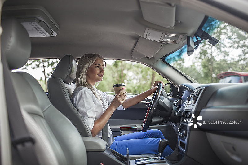 微笑的女商人拿着外卖咖啡开车图片素材