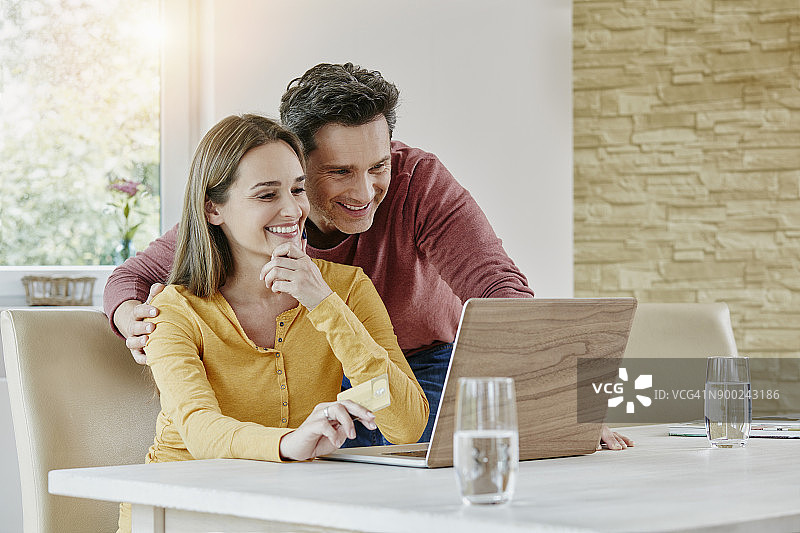 快乐的情侣在家网上购物图片素材