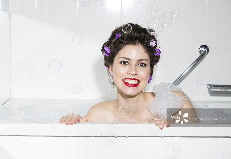 在浴缸里带着卷发微笑的年轻女子 portrait图片素材
