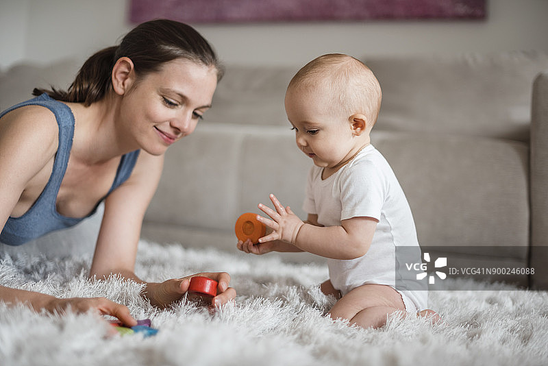 快乐的女婴和母亲在家中地毯上玩耍图片素材