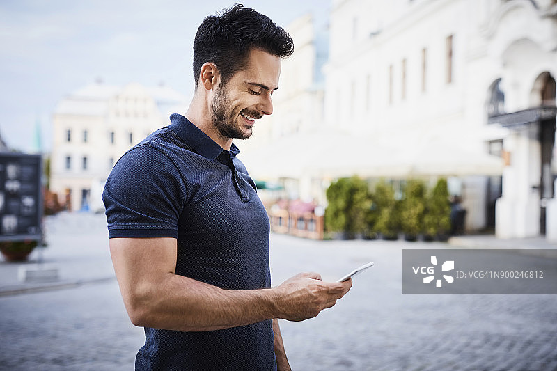 微笑的男人在城市里使用手机图片素材