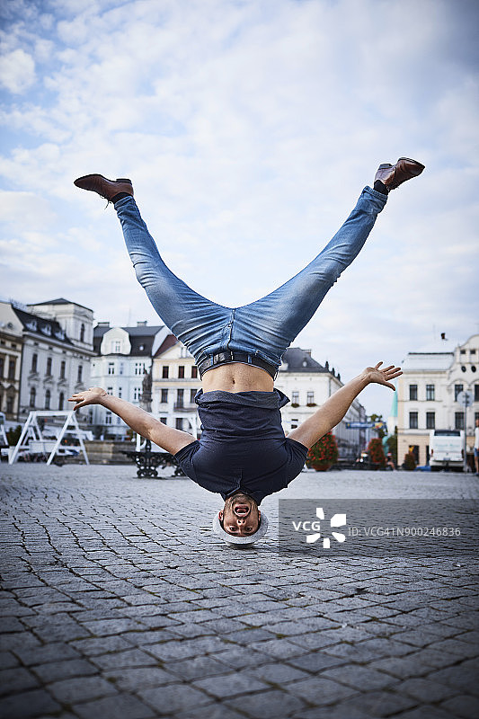 男人在城市广场上倒立，玩得很开心图片素材