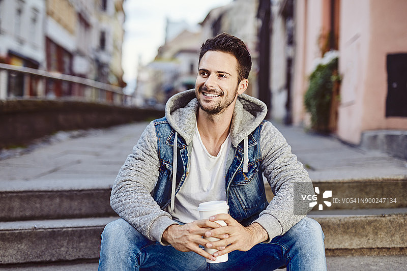 男人坐在楼梯上，背景是城市图片素材