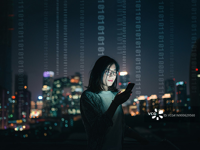 站在摩天大楼顶上拿着智能手机的女人图片素材