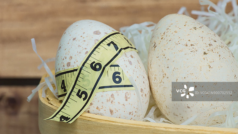 篮子里的两个火鸡蛋，一个用卷尺包裹图片素材