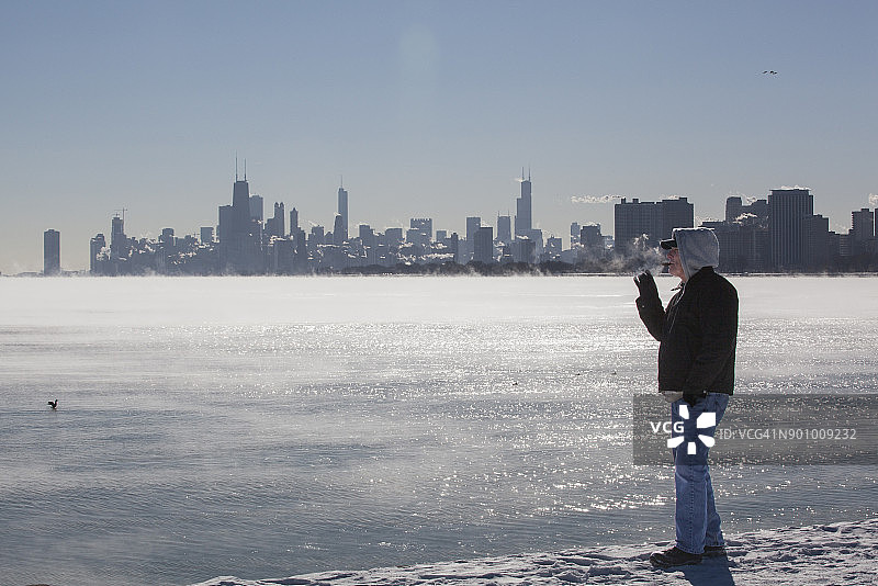 男人在寒冬的芝加哥天际线下抽雪茄图片素材