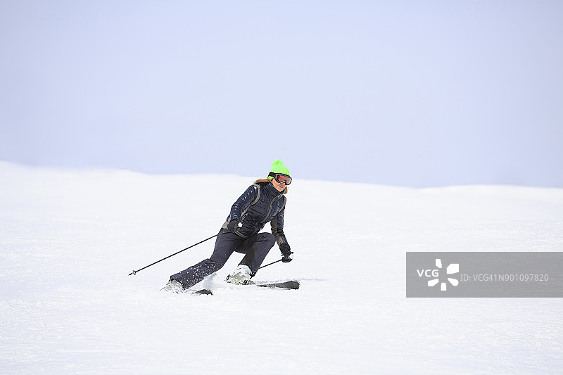 在阳光明媚的滑雪胜地滑雪的女子业余冬季运动图片素材