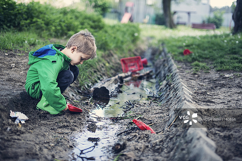 小男孩在满是垃圾的泥地里玩耍图片素材