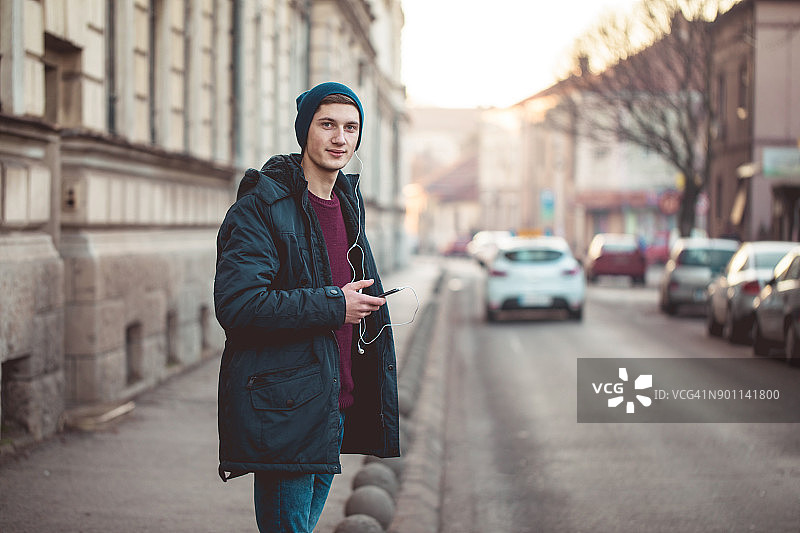 戴着耳机过马路的可爱的男人图片素材