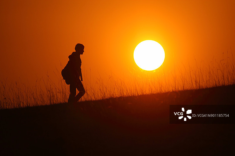 日落时分徒步旅行的男孩轮廓图片素材