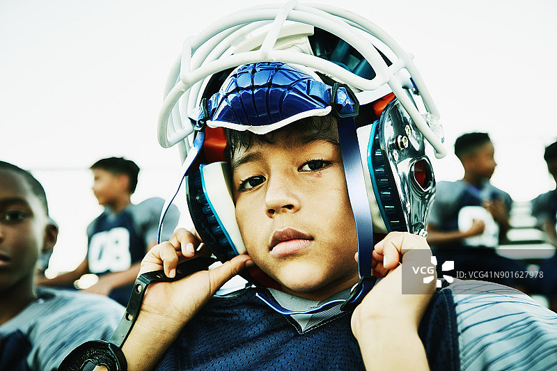 比赛前与队友坐在一起戴头盔的年轻足球运动员图片素材