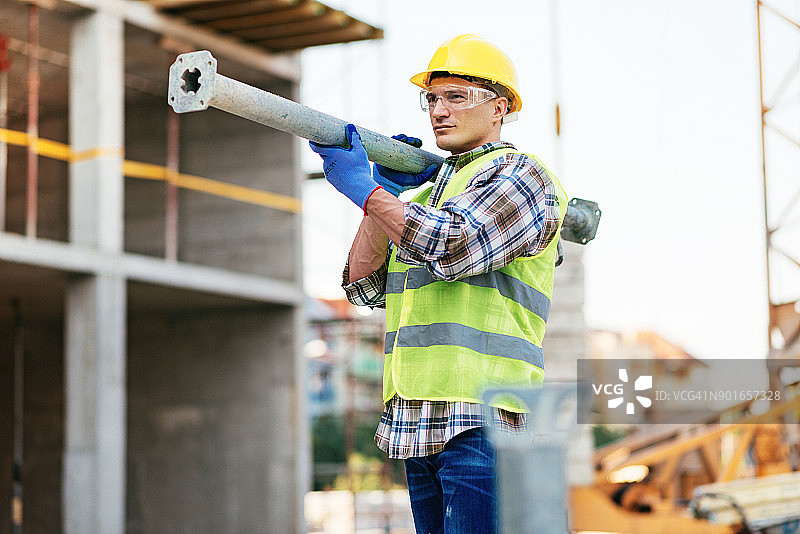 在建筑平台上工作的佩戴全套安全设备的手动建筑工人图片素材