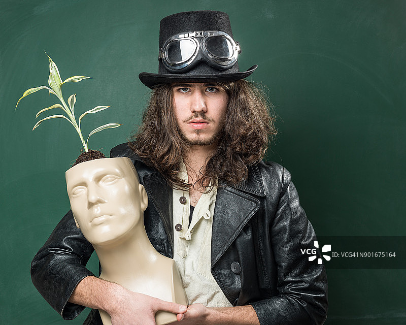 穿着蒸汽朋克风格服装的成年男人拿着人体模型头部图片素材