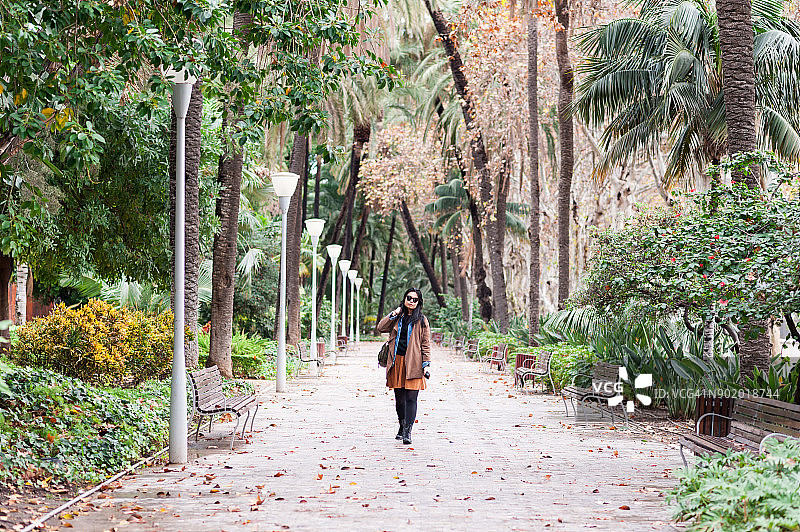 在西班牙马拉加郁郁葱葱的热带花园中行走的年轻女人图片素材