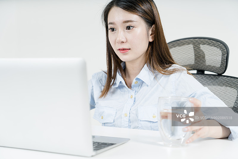 看电脑屏幕喝水的商务女性图片素材