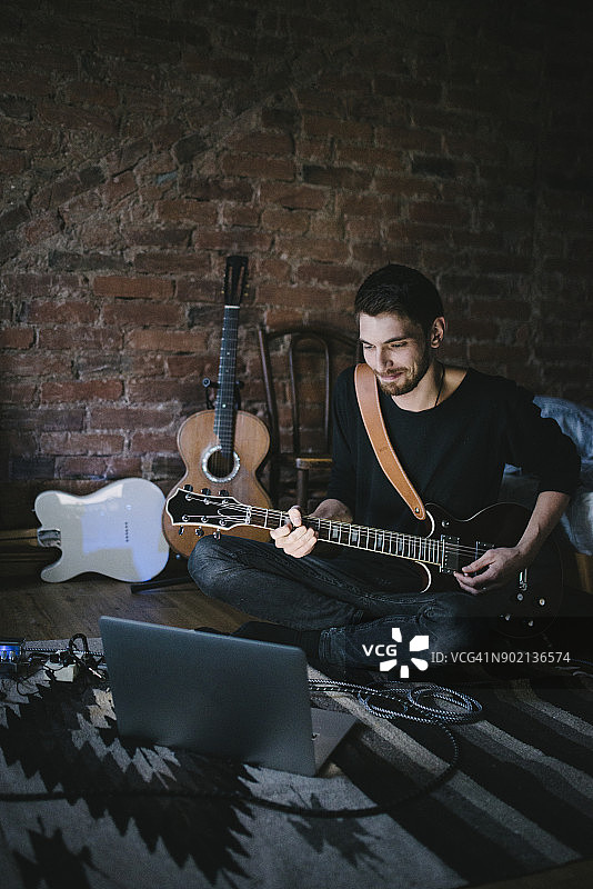 年轻音乐家弹吉他看笔记本图片素材