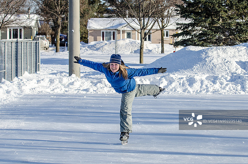 女子在户外溜冰场上做阿拉伯式花样滑冰动作图片素材