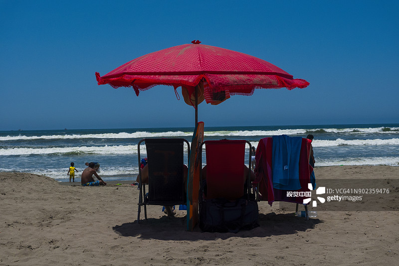 海滩上的红色雨伞和游泳者图片素材