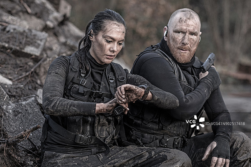 在废弃建筑工地行动中休息的红发男子和黑发女子军事特警反恐二人组图片素材
