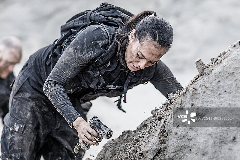 在沙丘上努力训练、互帮互助的红发男军人和棕发女军人图片素材