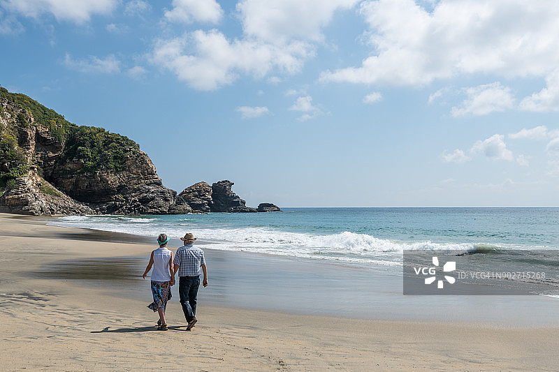 年长夫妇在海滩冲浪边缘散步图片素材