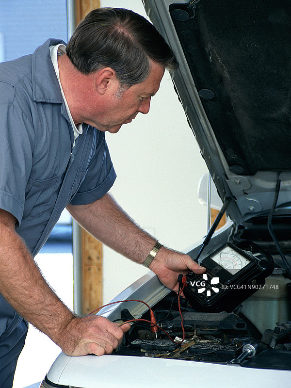 检查汽车电瓶的中年白人汽车修理工图片素材