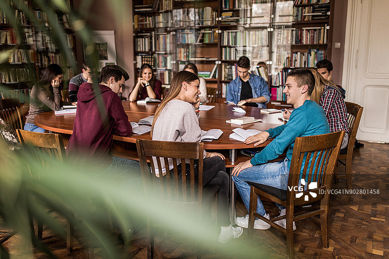 在图书馆与同学一起学习交流的青少年情侣图片素材