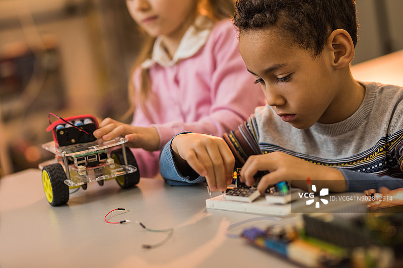 非裔美国男孩在实验室组装未来机器人的电气元件图片素材