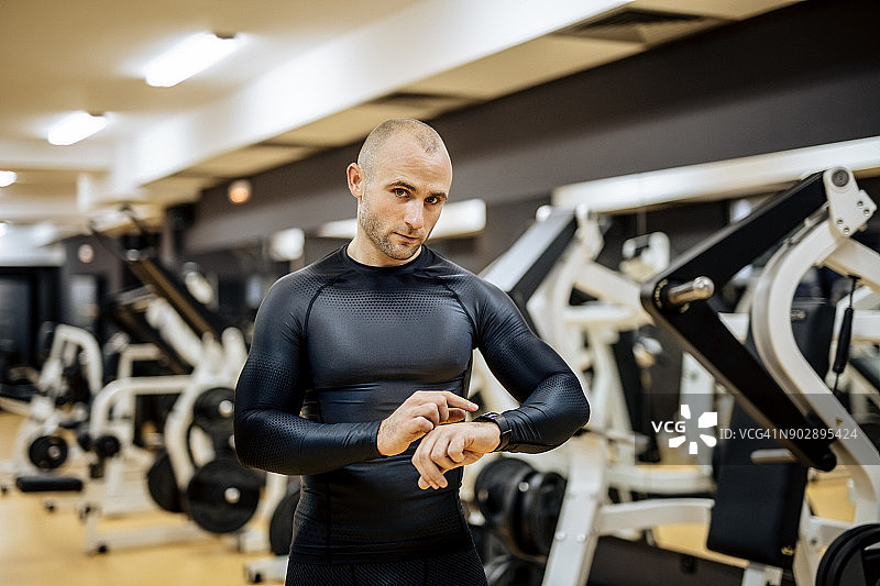 在健身房，年轻男人查看智能手表上的时间图片素材