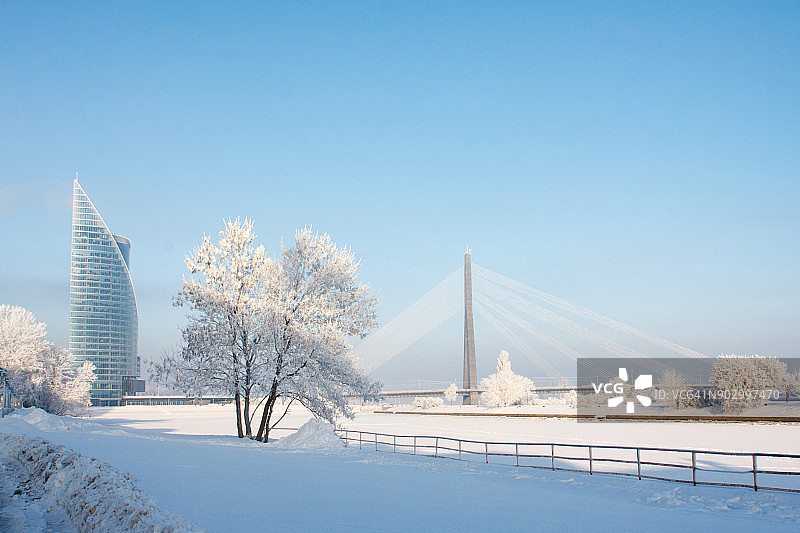白色城市景观：拉脱维亚里加的冬季雪景斜拉桥和摩天大楼图片素材