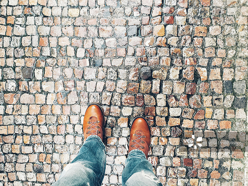 男子在鹅卵石街道上穿靴子的自拍图片素材