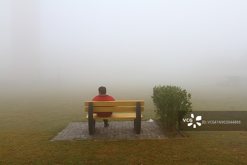 男人坐在雾中的长凳上图片素材