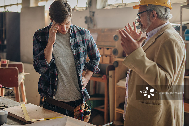 在车间里被质检员训斥的年轻体力工人图片素材