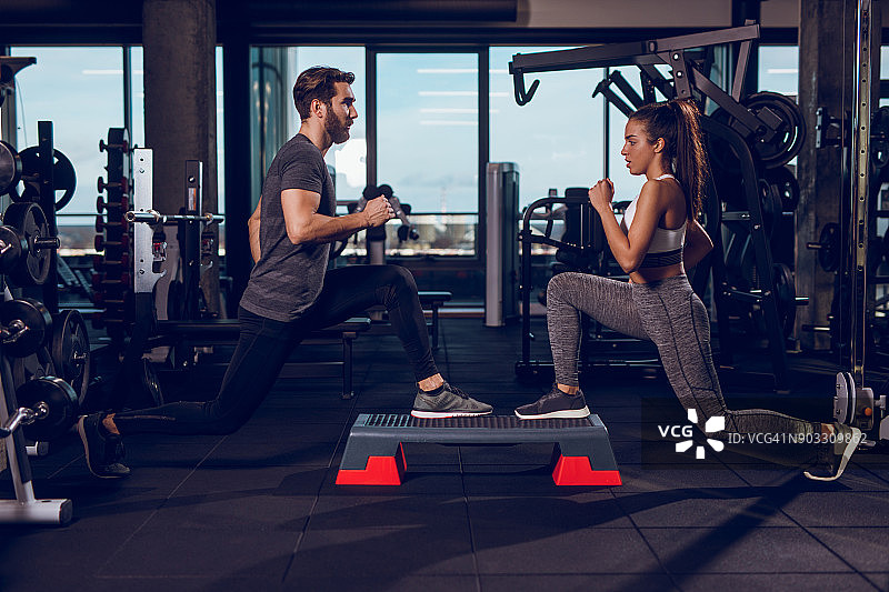 年轻人在健身房的踏步健美操器械上弓步图片素材