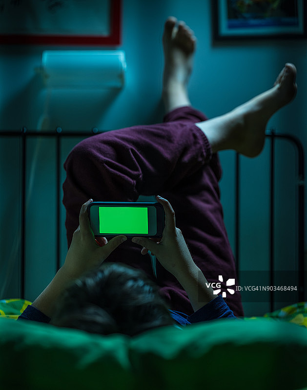 在床上使用绿幕的青少年图片素材