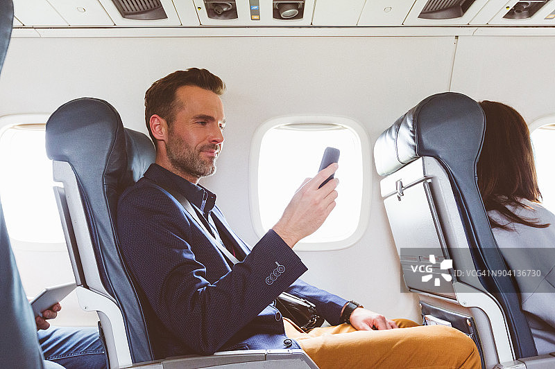 男人在飞机上使用手机图片素材