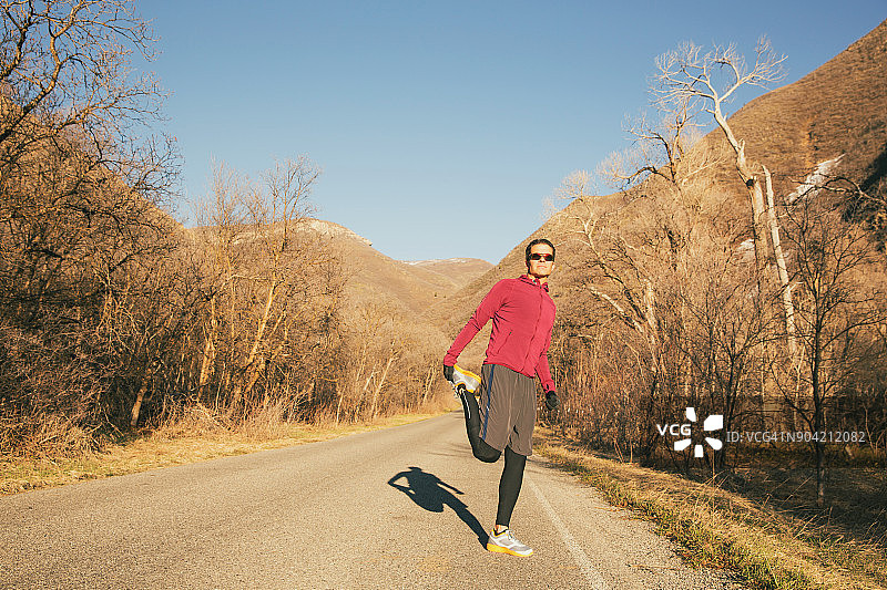 在冬季峡谷中伸展的成年男子跑步者图片素材