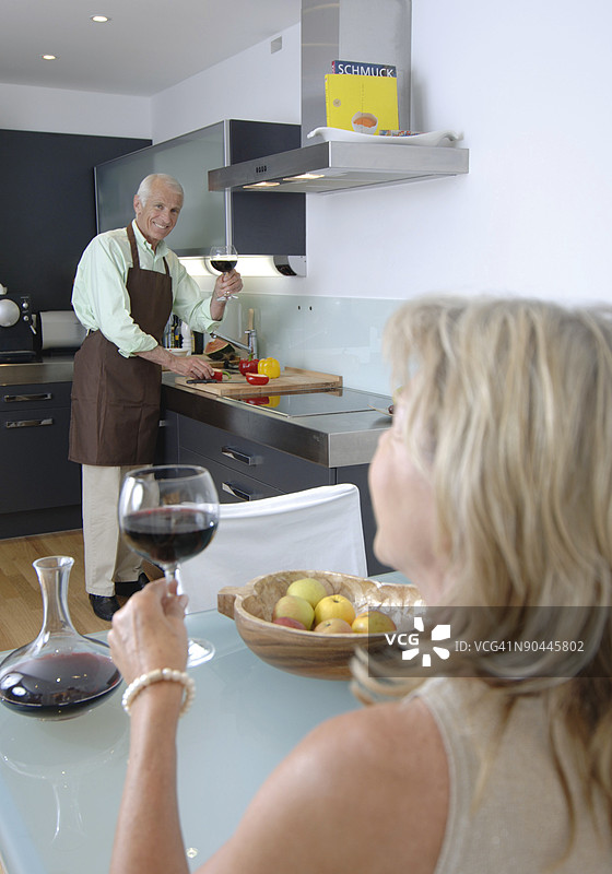 老年夫妇在厨房里享用红酒图片素材