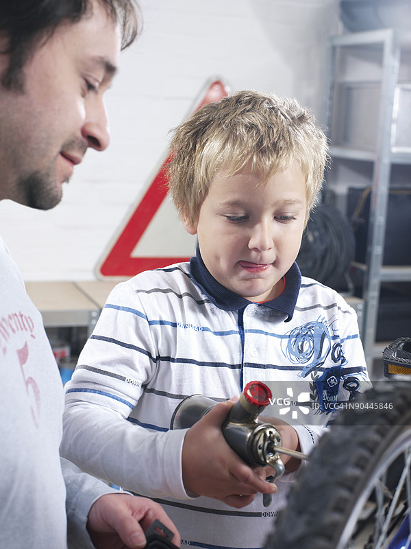 父亲和儿子在给自行车轮胎充气图片素材