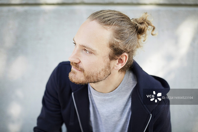 大学校园里靠墙站立的沉思的年轻男学生图片素材