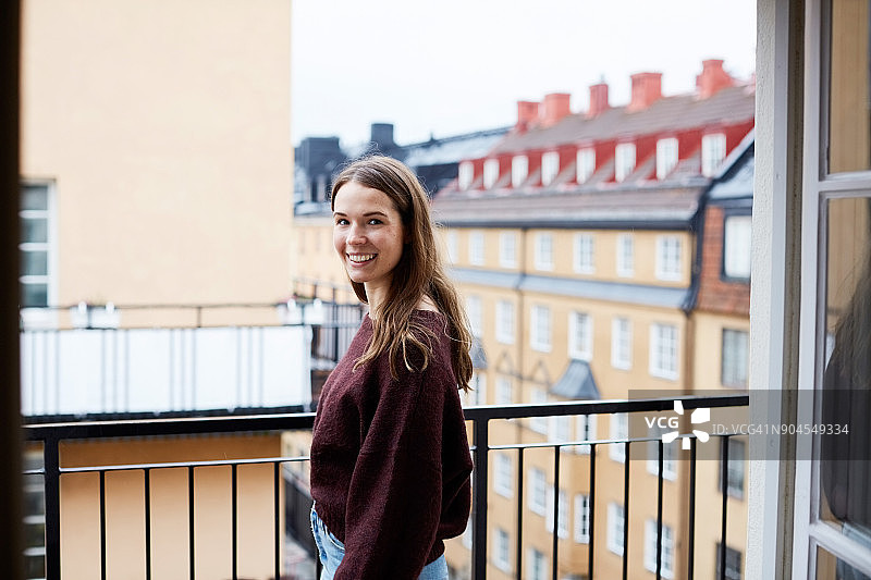 在出租公寓阳台上微笑的女人侧视图图片素材