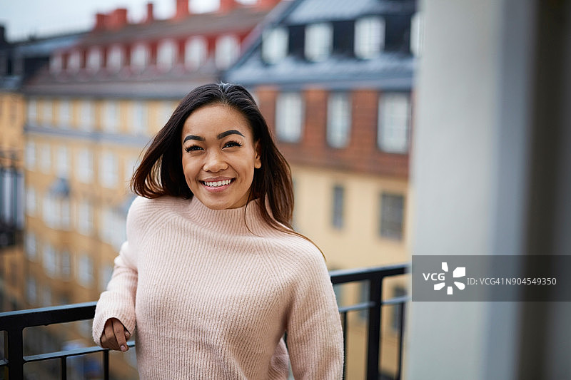 站在阳台上的快乐年轻女子图片素材