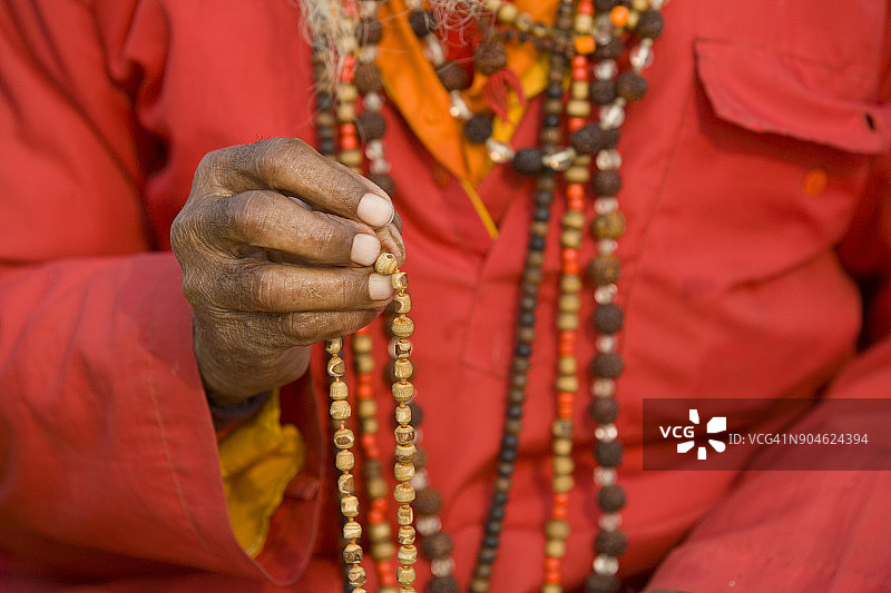 身穿红色长袍、佩戴念珠项链的人特写图片素材