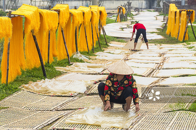 米粉生产场景：妇女在垫子上晾晒米粉，木杆上晾晒粉丝图片素材